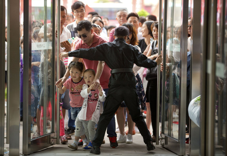 Image: A security guard opens the entrance doors for the grand opening of the Wanda Mall