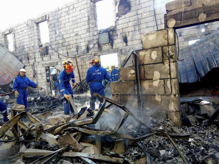 Image: Rescuers inspect the debris of a residential house after a fire broke out, in the village of Litochky