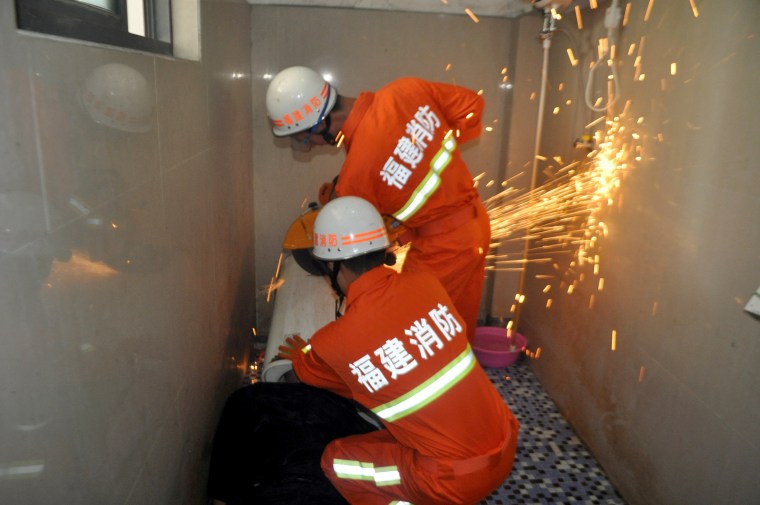 Image: Rescuers save a man with equipment as his head is stuck in a washing machine in Fuqing county of Fuzhou
