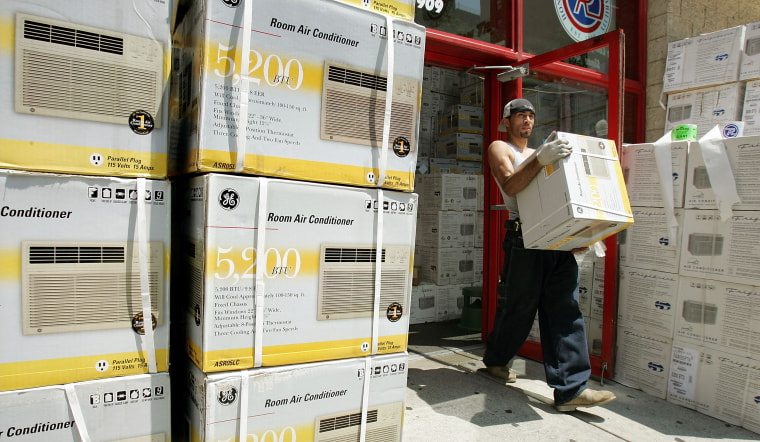 Image: A worker carries a new air conditioner out of a PC Richard store
