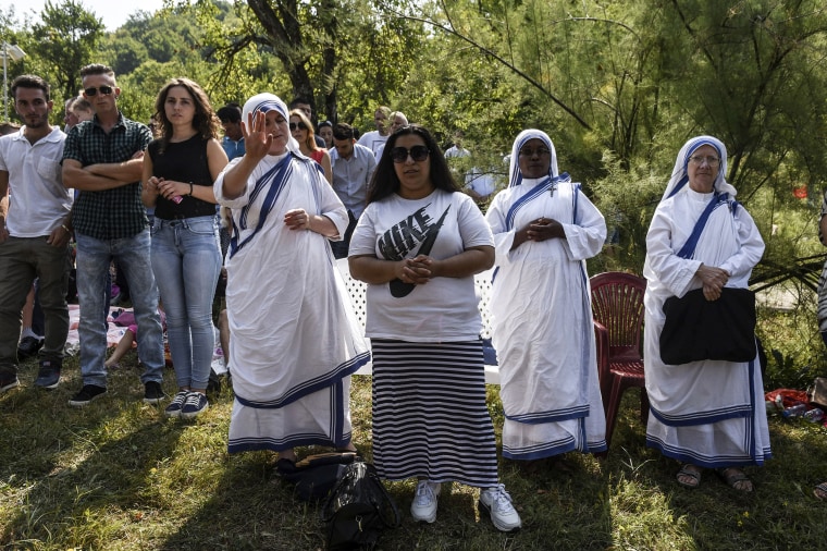 Image: Pilgrims pray near the church in the village of Letnica