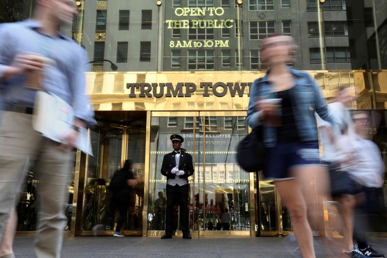Image: A doorman stands as people walk past the Trump Tower in New York