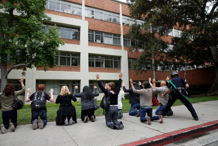 Image: A police officer conducts a search on people at the UCLA campus after it was placed on lockdown following reports of a shooter that left 2 people dead in Los Angeles, California