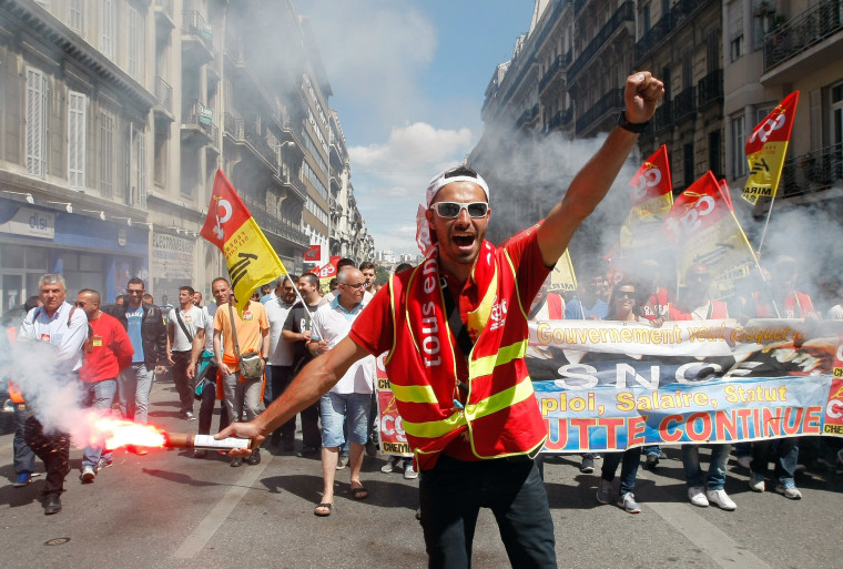 Image: A worker burns a flare during a demonstration in Marseille, Thursday, another day of strikes and protests against government labor reforms.