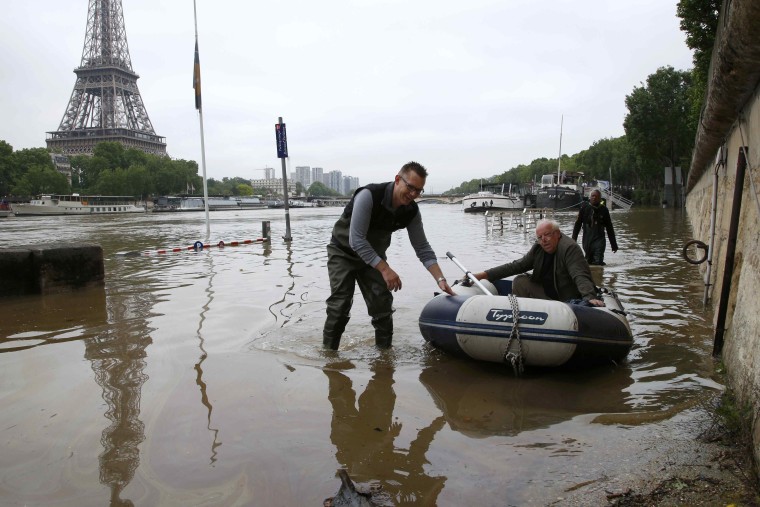 Image: A man uses a dinghy as he leaves his houseboat moored near the Eiffel towel during flooding on the banks of the Seine River in Paris