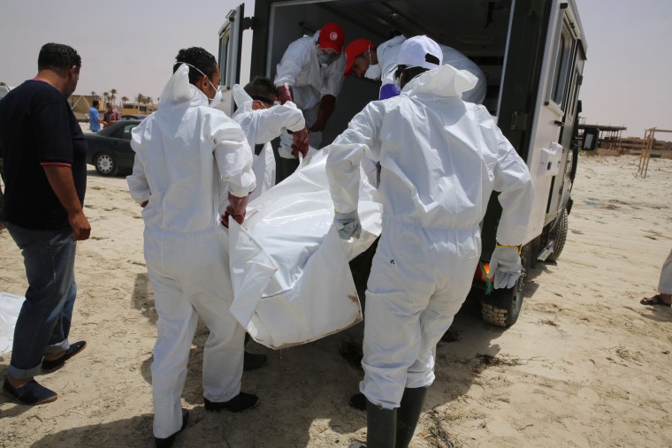 Image: Libyan officials remove a body from a beach