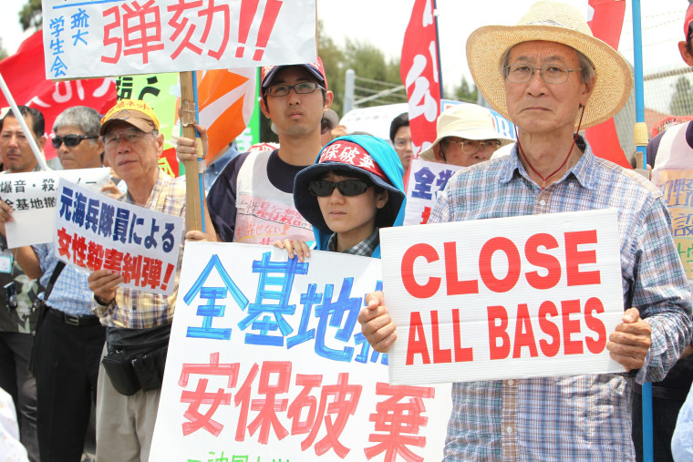 Image: Protesters hold signs outside Kadena Air Base on May 20.