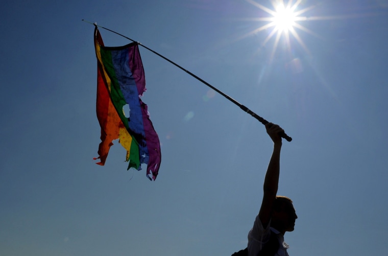 A gay rights activist waves a damaged rainbow flag during a gay pride in St. Petersburg on July 26, 2014.