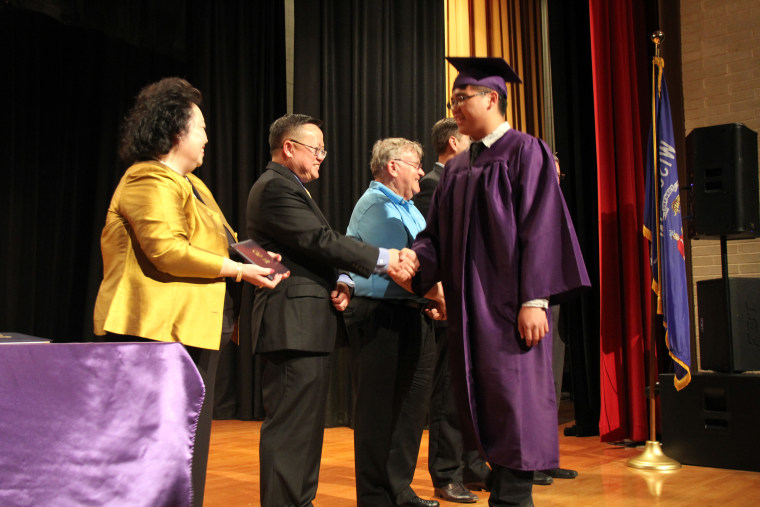 Chris Her-Xiong, the founder and executive director of the school, with graduation speaker Dr. Xa Xiong, and school boardmember Don Cohen congratulating a graduating senior.