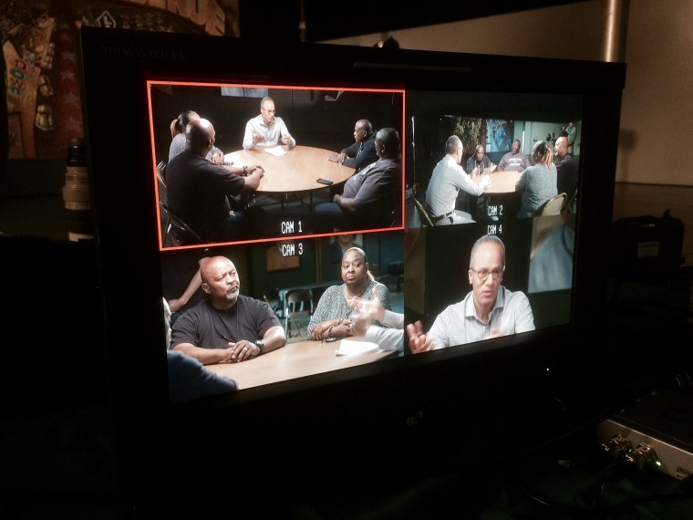 Lester Holt holds a round-table discussion with community members in Watts, South Los Angeles, to discuss police brutality, viewed through a multi-camera monitor.