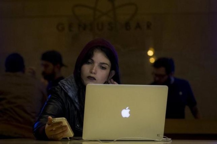 A customer uses an iPhone and a Macbook computer at the Genius Bar in the Apple Store at Grand Central Station in New York
