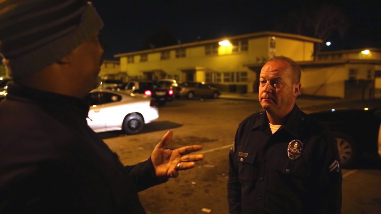 Watts Gang Task Force member Donny Joubert talks to LAPD Officer John Coughlin at the scene of a boy's arrest.