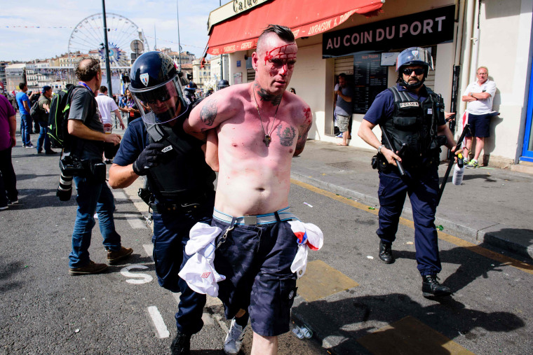 Image: An injured man is arrested following fights between England, Russian and French groups in Marseille