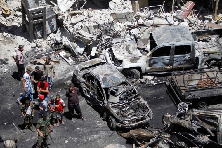 Image: People and Syrian Army members inspect a damaged site after a suicide and car bomb attack in south Damascus Shi'ite suburb of Sayeda Zeinab