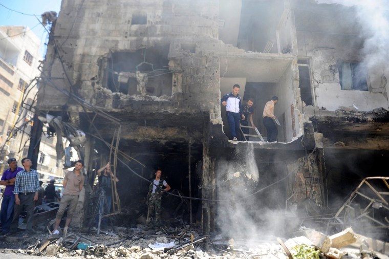 Image: People and Syrian Army members inspect a damaged site after a suicide and car bomb attack in south Damascus Shi'ite suburb of Sayeda Zeinab