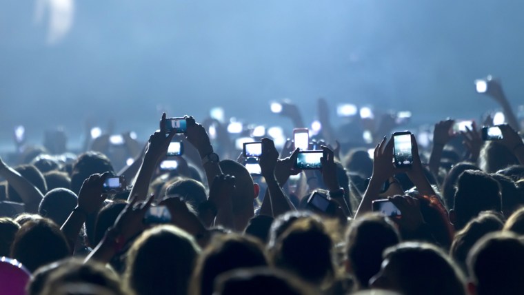 concert fans hold up cel phones