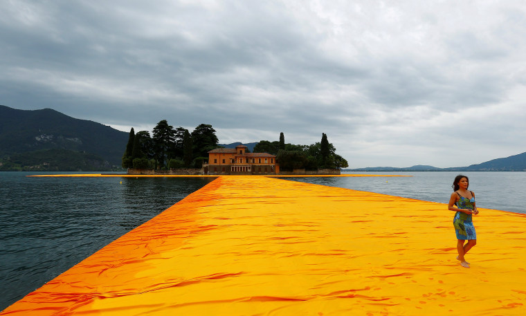 A woman walks on the installation 'The Floating Piers' by Bulgarian-born artist Christo Vladimirov Yavachev known as Christo, on the Lake Iseo, northern Italy, June 16, 2016.REUTERS/Stefano Rellandini