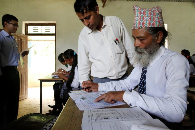 Image: A teacher helps Kami fill out his registration form to apply for upcoming exams