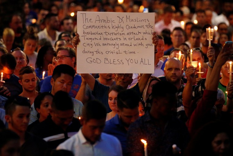 Image: A man holds up a sign saying Arab Muslims condemn the attack as he takes part in a candlelight memorial service the day after a mass shooting at the Pulse gay nightclub in Orlando