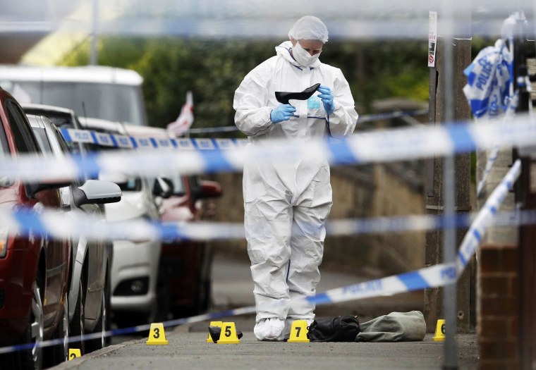 Image: Forensics police officers collect a woman's shoes on the ground behind a police cordon in Birstall near Leeds