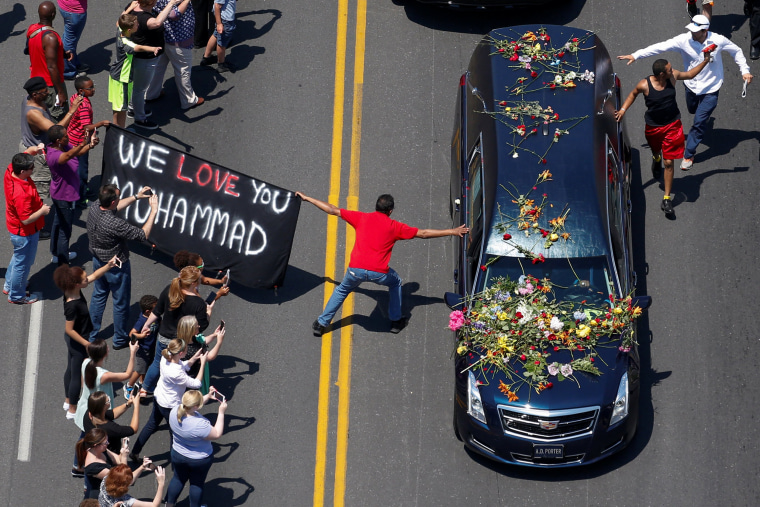 Image: Well wishers holding a banner touch the hearse carrying the body of Muhammad Ali in Louisville Kentucky