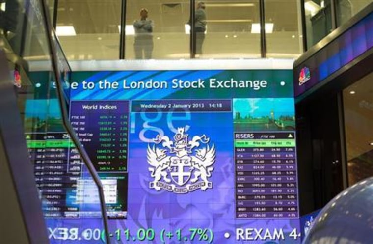 Workers speak above an electronic information board at the London Stock Exchange in the City of London