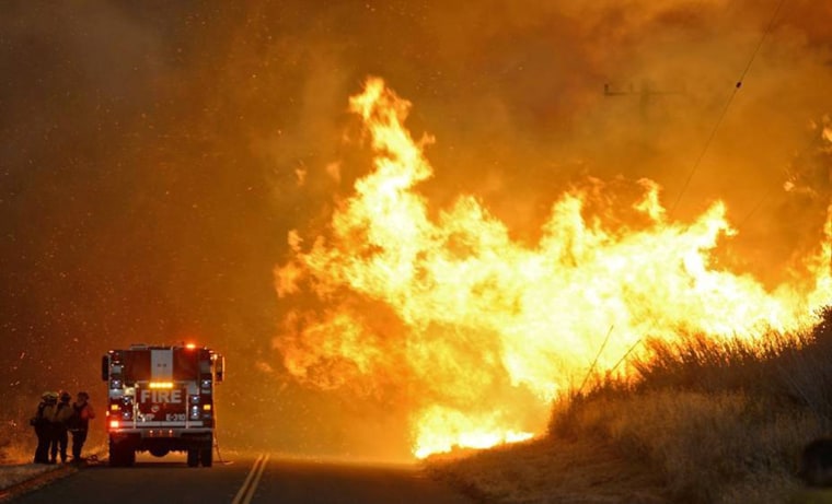 Image: A fire crew takes shelter behind an engine as the Sherpa Fire advances