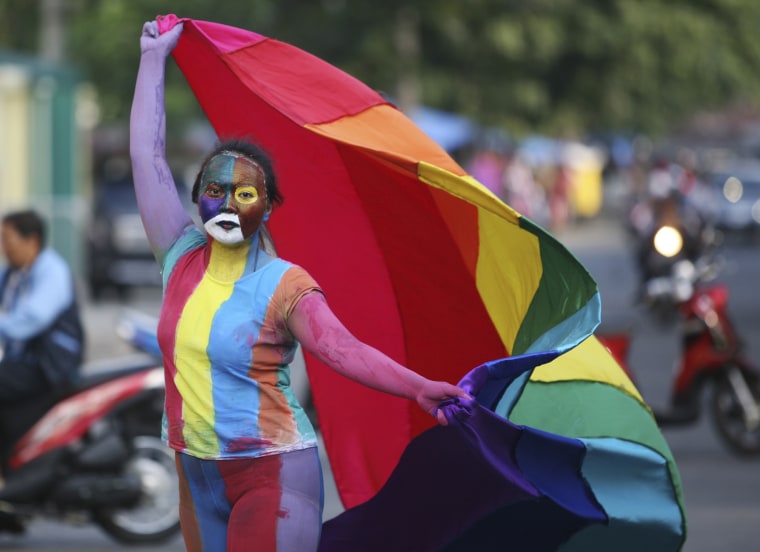 Image: An Indonesian activist with painted face and body waves a flag during a protest demanding LGBTQ equality