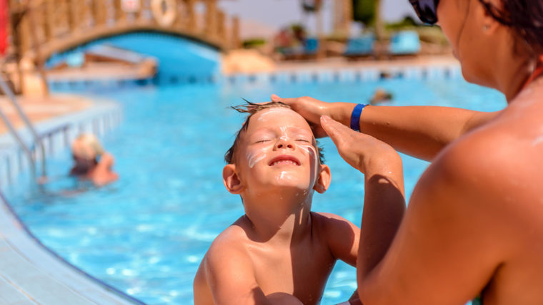 Mother putting sunscreen on her child