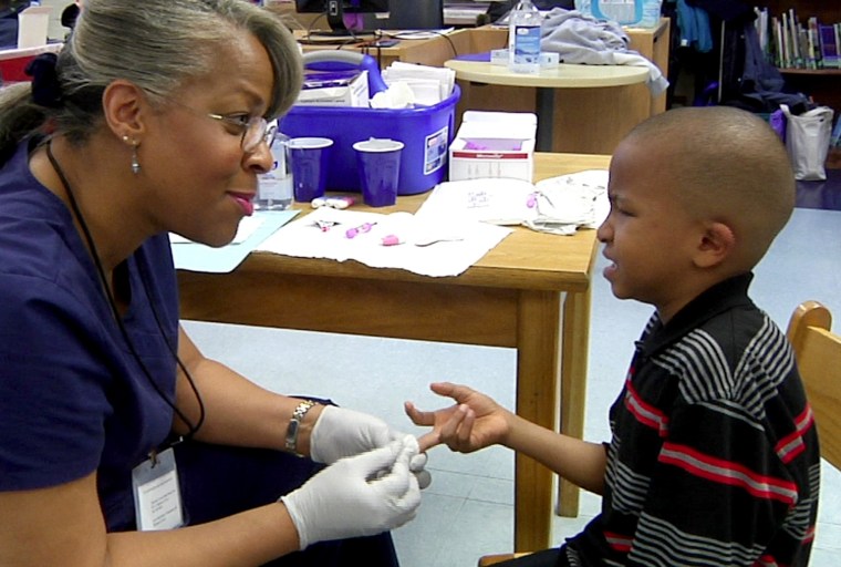 University of Michigan-Flint lecturer Veronica Robinson draws blood from 7-year-old Zyontae during a lead-testing clinic held at Richfield Public School Academy in Flint, Mich. on March 24, 2016.