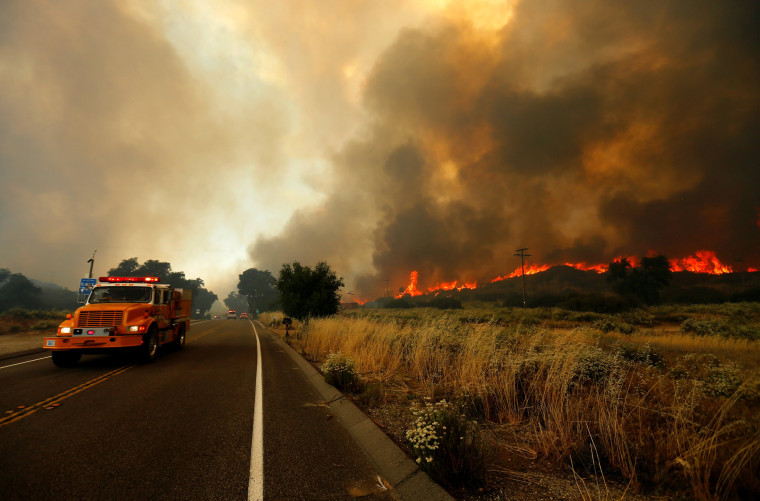 Image: Firefighters move to try and head off a fast moving wildfire as it burns near Potero, California