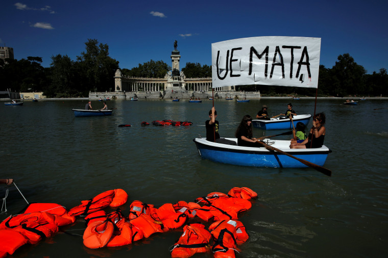 Image: Activists hold a banner that reads \"European Union kills\" in a boat next to floating life jackets as people row rental boats during a protest to mark World Refugee Day at Retiro park in Madrid