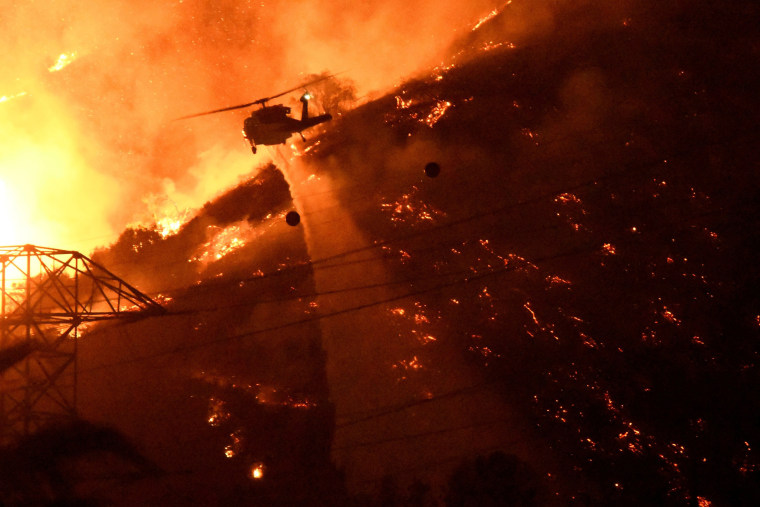 Image: A Los Angeles County fire helicopter makes a night drop while battling the so-called Fish Fire above Azusa, California