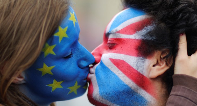 Image: Two activists with the EU flag and Union Jack painted on their faces kiss each other in front of Brandenburg Gate to protest against Brexit in Berlin