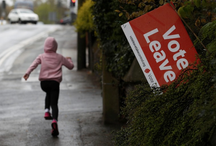 Image: A girl runs past a Vote Leave sign, protruding from the garden of a house in Altrincham