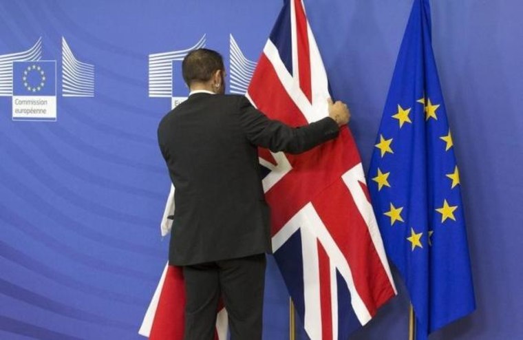 An employee at the European Commission adjusts a British flag ahead of the meeting between Prime Minister Cameron and European Commission President Juncker in Brussels