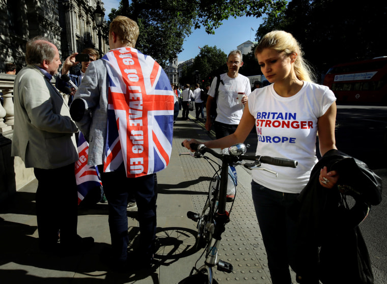 Image: A vote remain supporter walks past a vote leave supporter outside Downing Street in London