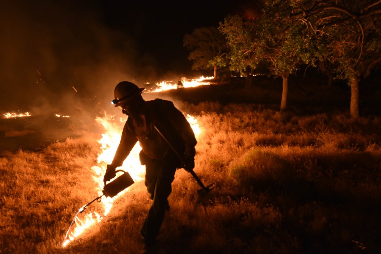 A Kern County firefighter sets a backfire by a wildfire burning near Lake Isabella, Calif. on Friday, June 24, 2016.  Dozens of homes burned to the ground as a wildfire raged over ridges and tore through rural communities in central California, authorities said.