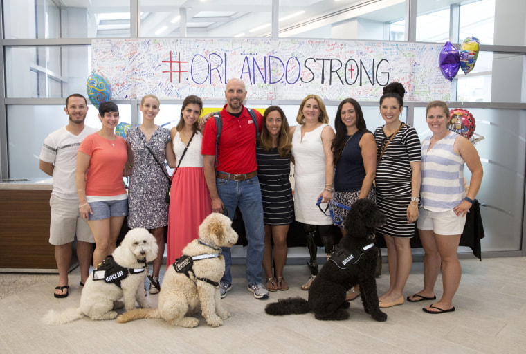 Boston Marathon bombing survivors visit Orlando Regional Medical Center to meet with Pulse shooting survivors. From left: Nick Yanni, Lee Ann Yanni, Eliza Gedney, Sydney Corcoran, Dave Fortier, Nicole O'Neil, Celeste Corcoran, Sabrina Dello Russo, Michelle L'Heureux and Elizabeth Birmingham. Front row service dogs Koda, Zealand and Sebastian.