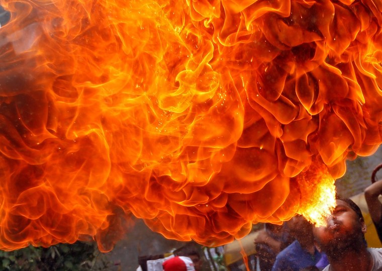 Image: A Hindu devotee performs a stunt with fire during a rehearsal for the annual Rath Yatra in Ahmedabad