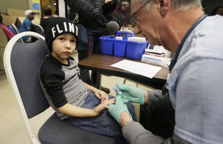 Image: A nurse draws a blood sample from a child in Flint