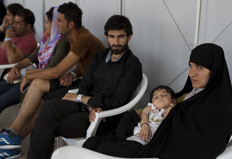 Image: Afghan migrants who live in the Hellenikon refugee and migrant camp register for asylum