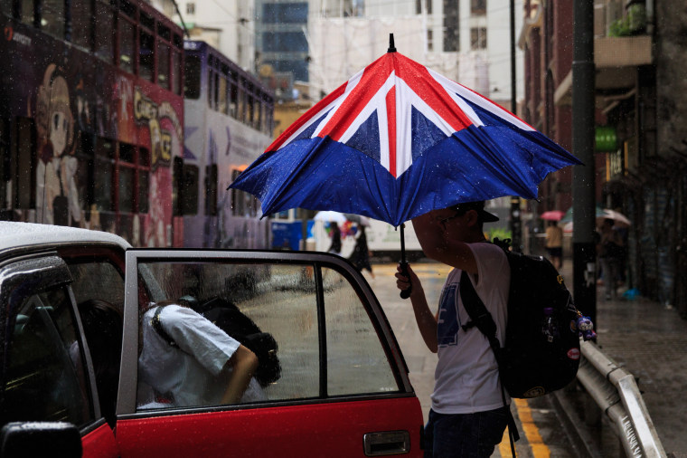 Image: A man closes his umbrella designed like the British flag