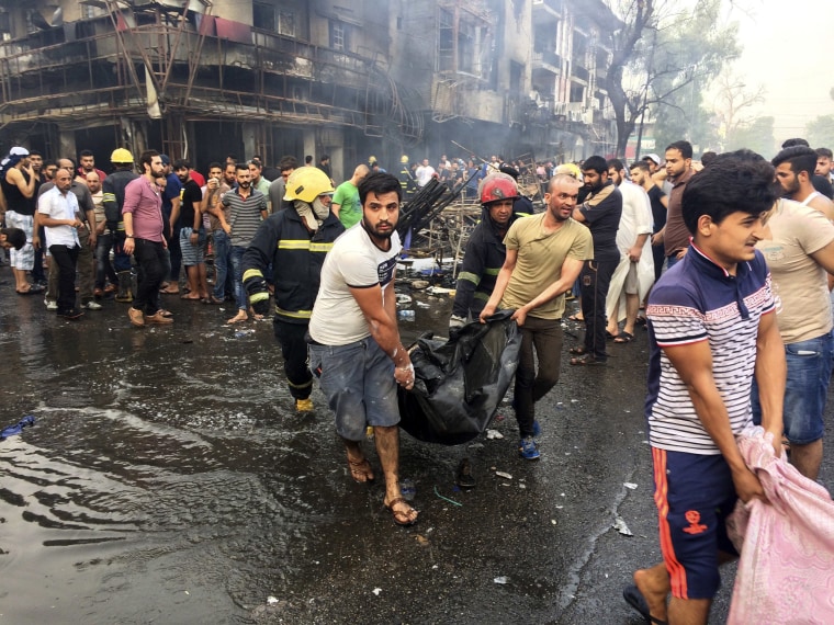 Image: Iraqi firefighters and civilians carry bodies of victims killed in a car bomb