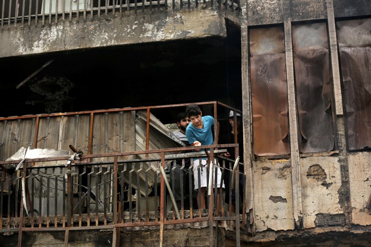 Image: Iraqi men looks for victims who went missing after a car bomb hit Karada