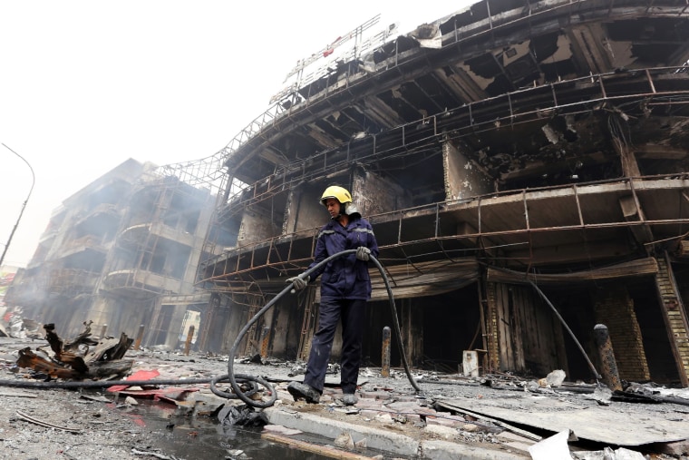 Image: An Iraqi firefighter works at the site of a suicide car bombing