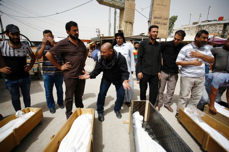 Image: Iraqi men mourn over bodies after they lost five members of their family