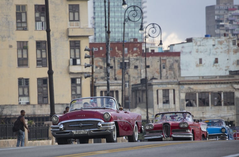 Fashion models are driven in vintage American convertible cars along the Malecon in Havana, Cuba.