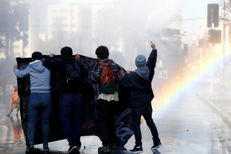 Image: Demonstrators clash with riot policemen during an unauthorized march called by the Chilean student federations to protest against government's education reform, in Santiago