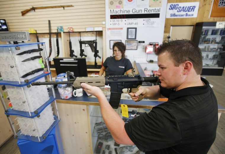 Image: An employee shows an AR-15 semi-automatic gun to a customer